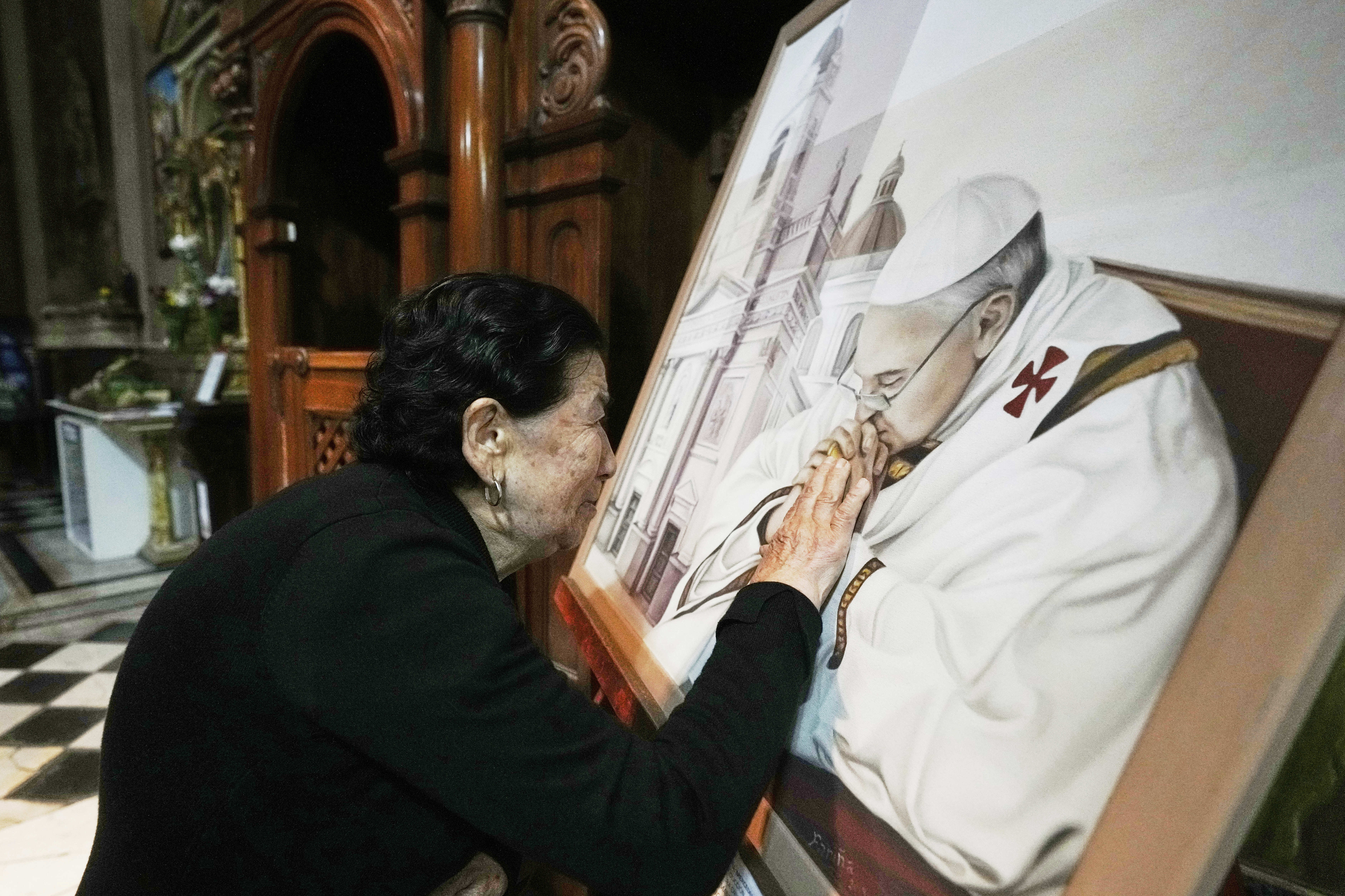 Genali Nogales touches a painting of the late Pope Francis at the Basílica de San José de Flores, where he worshipped as a youth, following the Vatican's announcement of his death in Buenos Aires, Argentina, April 21, 2025. (Gustavo Garello/AP)