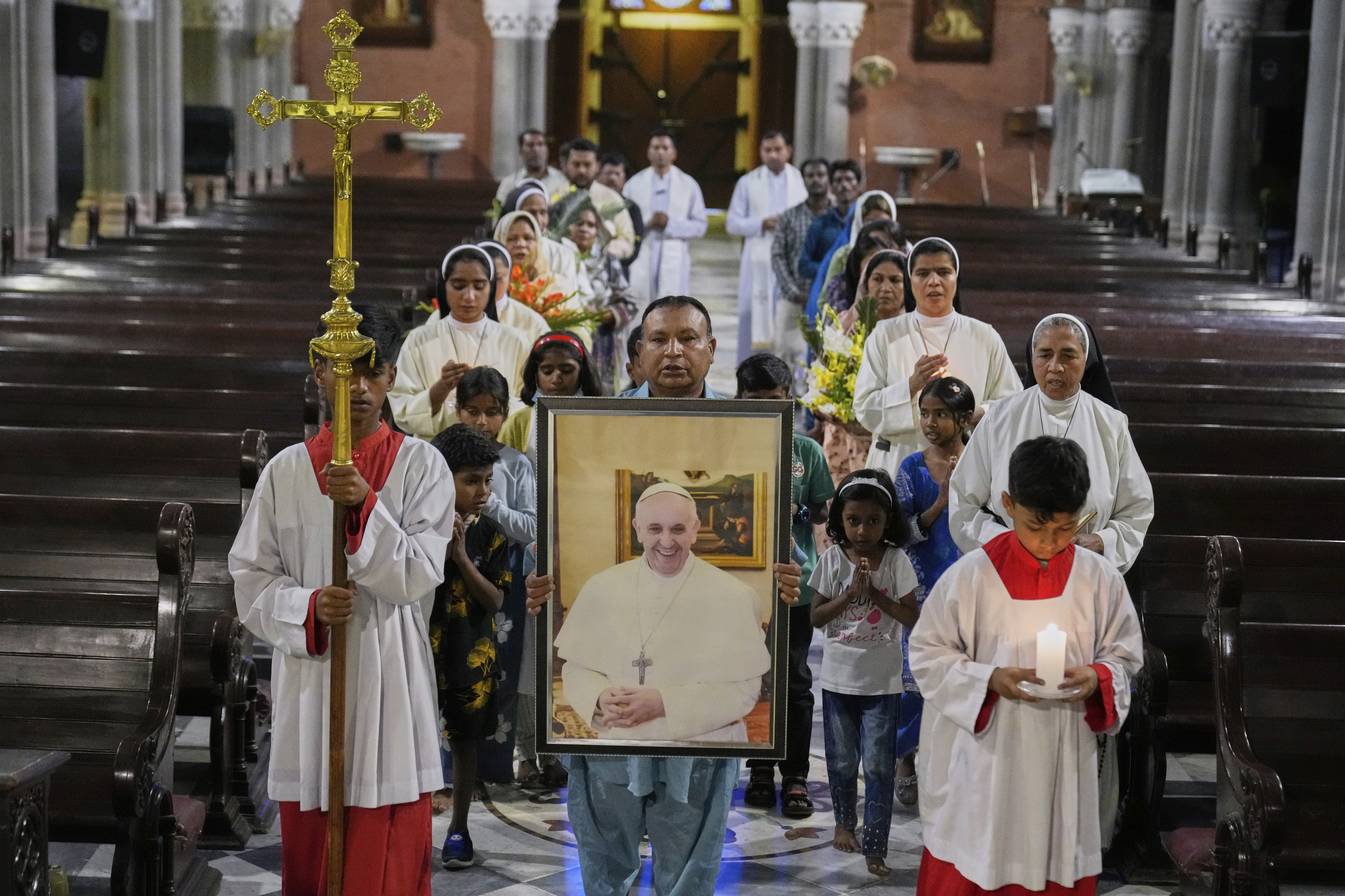 Christians arrive with a portrait of Pope Francis for a prayer ceremony at the Cathedral Church of the Resurrection, in Lahore, Pakistan, April 21, 2025, following the announcement by the Vatican of the death of Pope Francis. (K.M. Chaudary/AP)