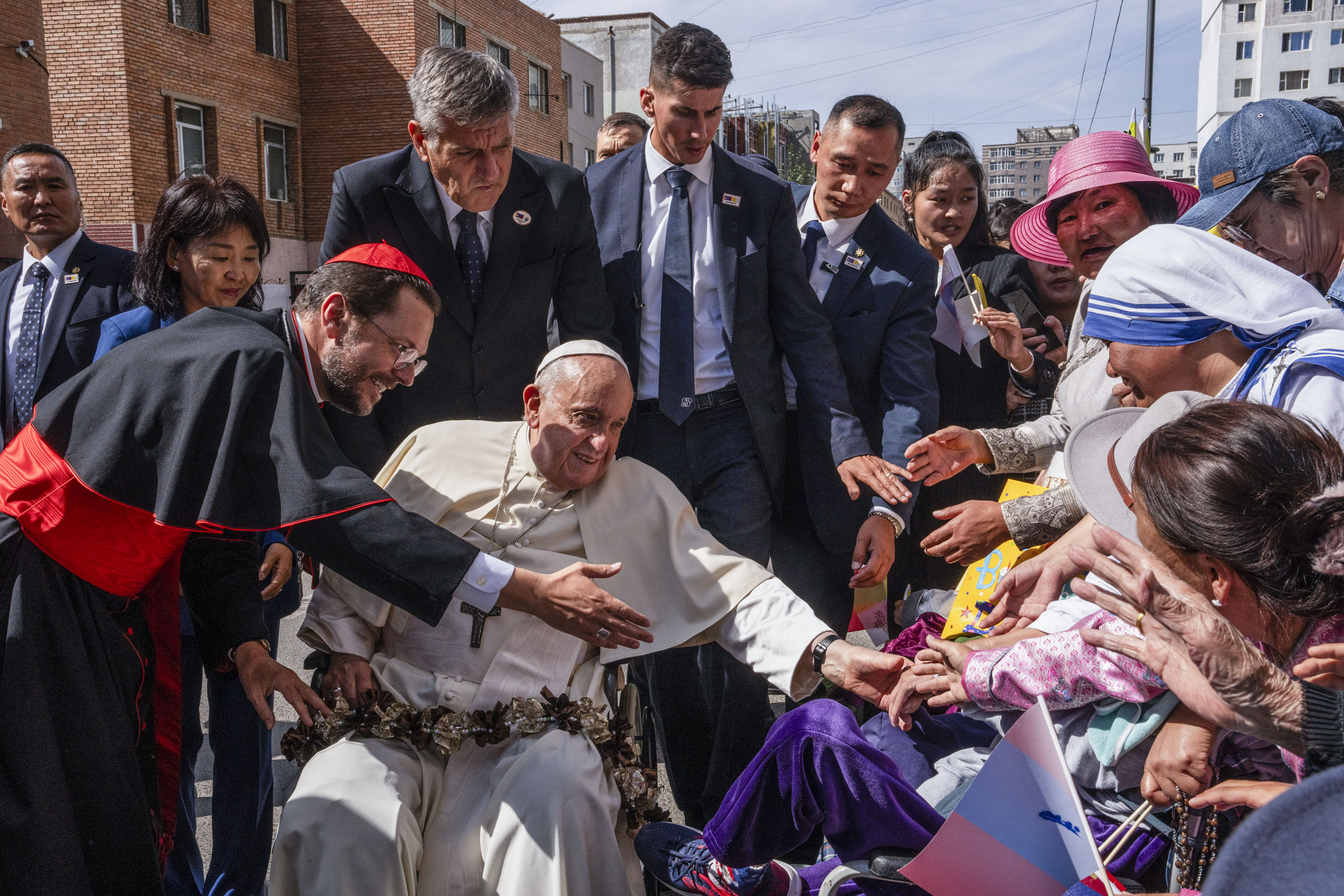 Pope Francis is greeted by Cardinal Giorgio Marengo, left, Apostolic Prefect of Ulaanbaatar, and faithful gathered outside the Apostolic Prefecture in Ulaanbaatar's Kahn Uul district, Sept. 1, 2023. Pope Francis is traveling to Mongolia to encourage one of the world's smallest and newest Catholic communities. It's the first time a pope has visited the Asian country and comes at a time when the Vatican's relations with Mongolia's two powerful neighbors, Russia and China, are once again strained. (Louise Delmotte/AP)