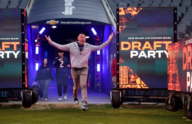 Ryan Kunkel, of Glen Ellyn, acts like a player being announced as he emerges from the tunnel after visiting the Bears locker room during the Bears draft party at Soldier Field on April 24, 2025. (Chris Sweda/Chicago Tribune)