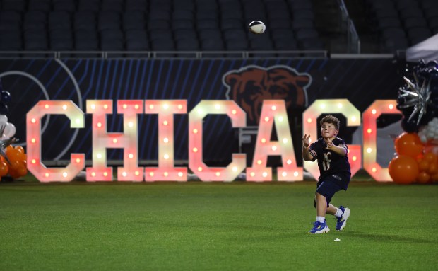 A young boy catches a football on the field while attending the Bears draft party at Soldier Field on April 24, 2025. (Chris Sweda/Chicago Tribune)