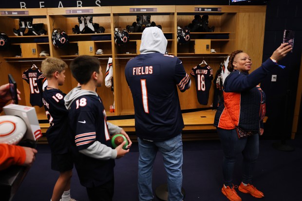 A woman takes a photograph in front of a Caleb Williams jersey hanging as fans tour the locker room during a Bears draft party at Soldier Field on April 24, 2025. (Chris Sweda/Chicago Tribune)