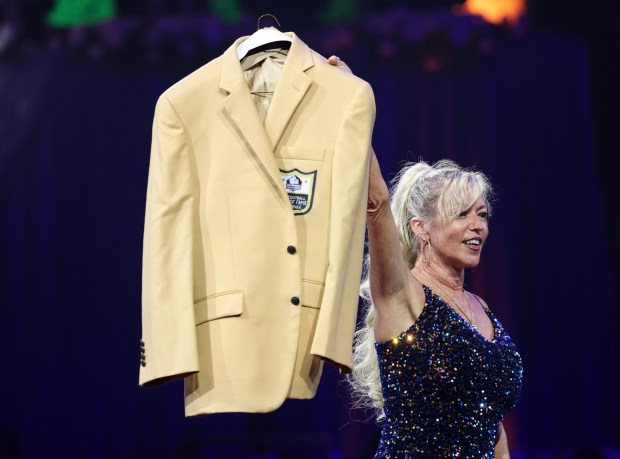 Misty McMichael raises Steve McMichael's gold jacket during the Pro Football Hall of Fame Enshrinees' Gold Jacket Dinner at the Canton Civic Center on Aug. 2, 2024, in Canton, Ohio. (John J. Kim/Chicago Tribune)