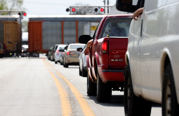 A long line of stopped vehicles wait as a freight train comes to a complete stop near 140th Street and Western Avenue in Dixmoor, April 28, 2025. (Antonio Perez/Chicago Tribune)