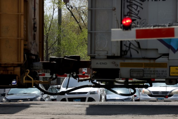 Vehicles wait for a stopped freight train on Seeley Avenue in Dixmoor, April 28, 2025. The village received a grant for a feasibility study to explore solutions to reduce traffic congestion caused by trains that sometimes block crossing for hours. (Antonio Perez/Chicago Tribune)