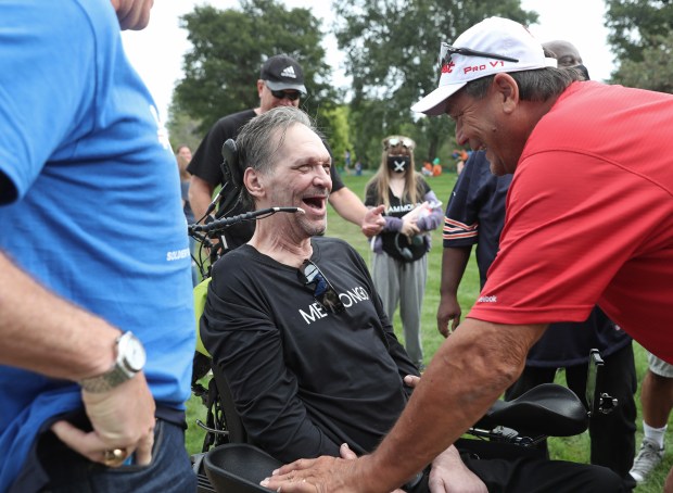 Former Chicago Bears players Steve McMichael, center, and Dan Hampton, right, laugh as they greet each other before the ALS Walk for Life at Soldier Field, Sept. 18, 2021, in Chicago. McMichael, who was diagnosed with ALS, received the Les Turner ALS Foundation Courage Award during the opening ceremony. (John J. Kim/Chicago Tribune)