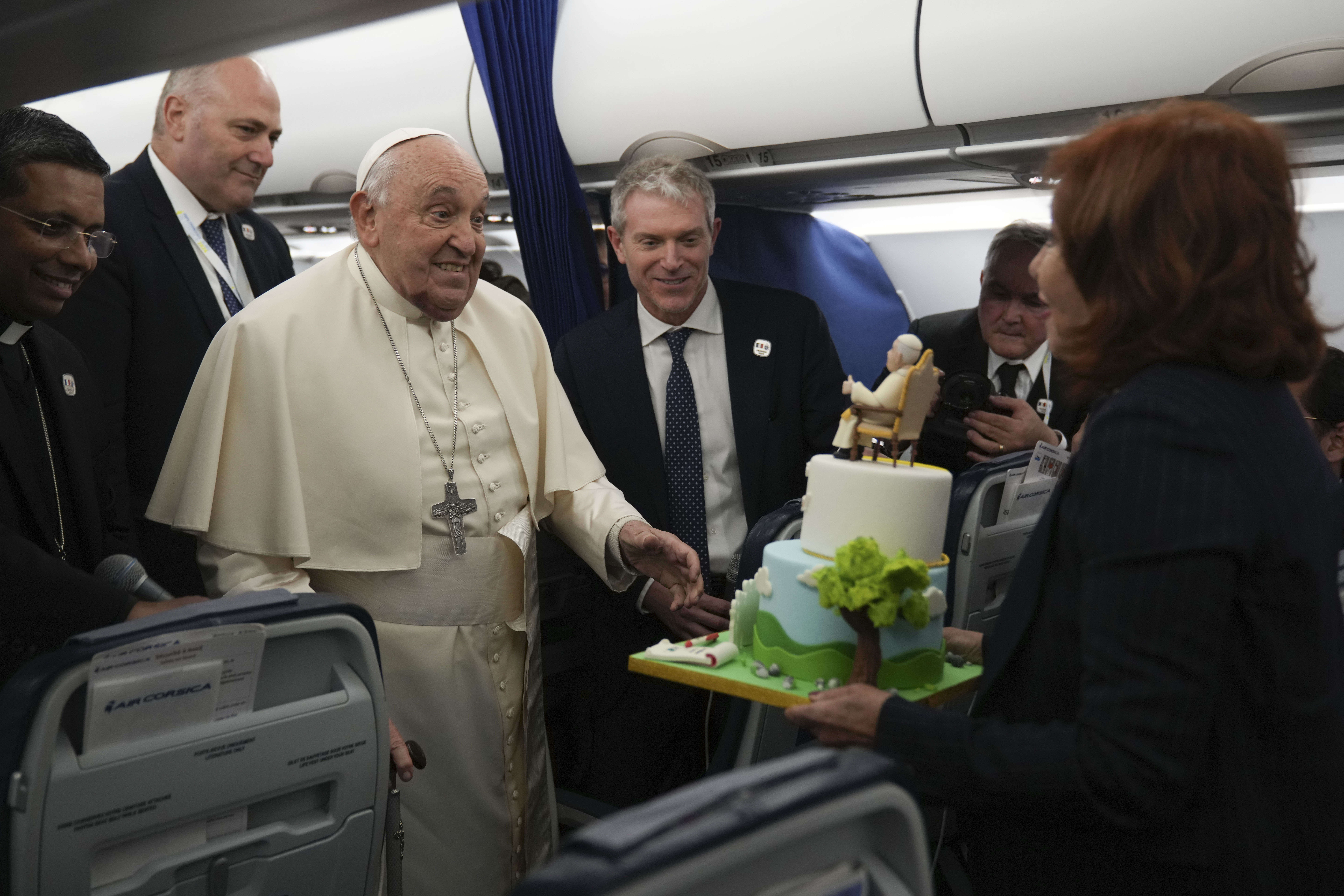 Pope Francis is presented with a cake by Valentina Alazraki, correspondent for TeleVisa Univision, to celebrate his upcoming Dec. 17, 88th birthday, on the flight back to Rome at the end of his one-day visit to Ajaccio in the French island of Corsica, Dec. 15, 2024. (Alessandra Tarantino/AP)